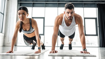 young woman and young men are doing push-ups