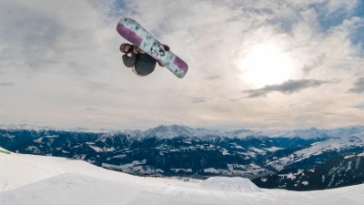 Snowboarders Yannek Konda and Moritz Amsuess flying through the air, Amsuess filming Konda doing a trick with an action cam.